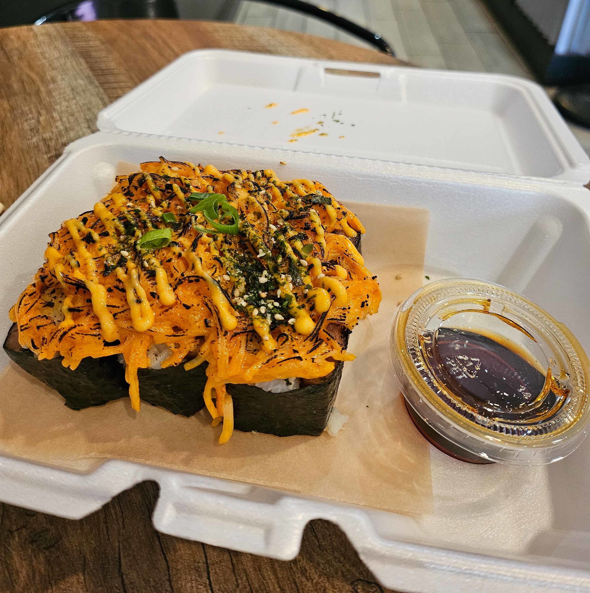 musubi in a to go container with crab meat and toppings